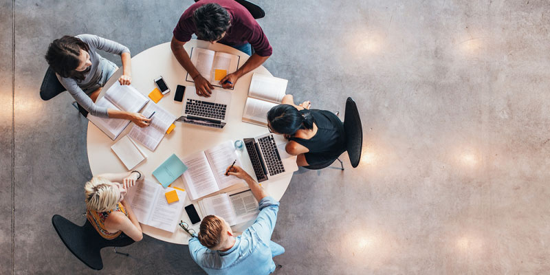 Top down photograph of people working together around a round table.