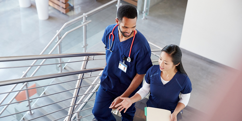 Two healthcare workers talking whilst walking up the stairs