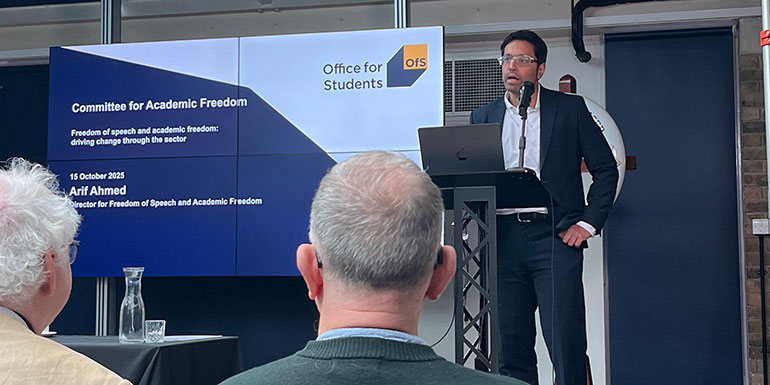 Photograph of Arif Ahmed on stage at the conference.