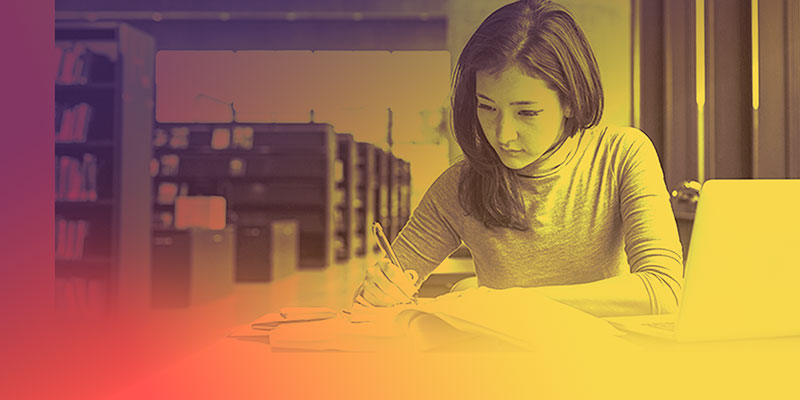 Female higher education student working in a library